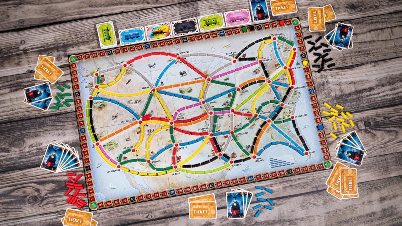 Mapa ferroviário de tabuleiro com cartas e vagões coloridos.