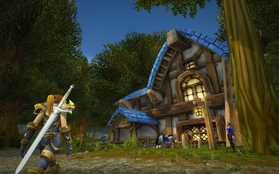 Personagem humano se aproxima da pousada de Goldshire por uma estrada cercada de árvores